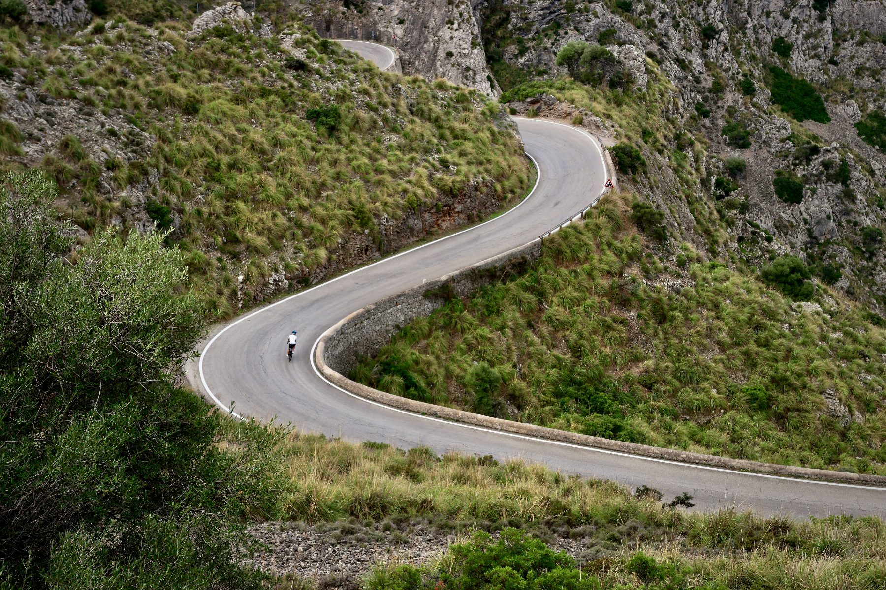 A lone cyclist on a winding mountain road